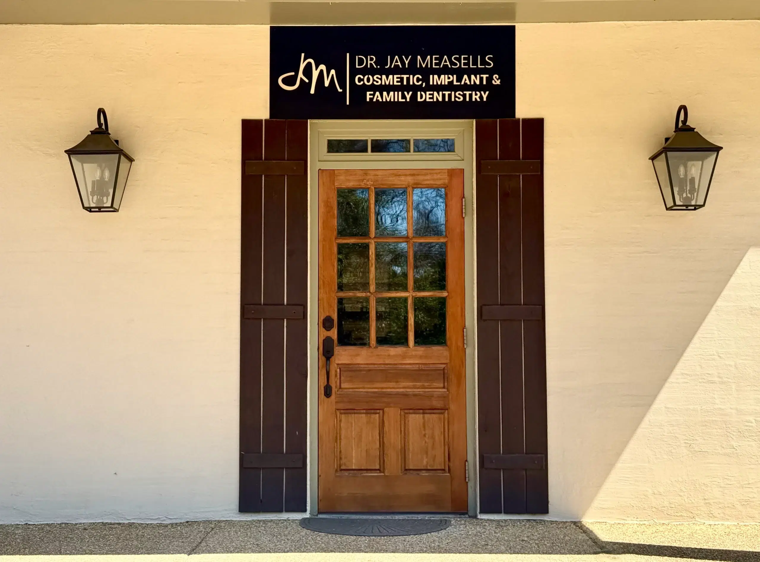 Front entrance of the Dr. Jay Measells office: a wooden door beneath the practice sign, between two lanterns